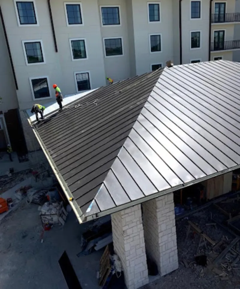 Crew installing standing seam metal roof panels on a commercial project in Olathe